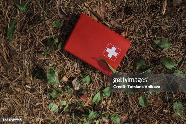 photo of red first aid kit box lying on pine-needle covered earth - safety kit imagens e fotografias de stock