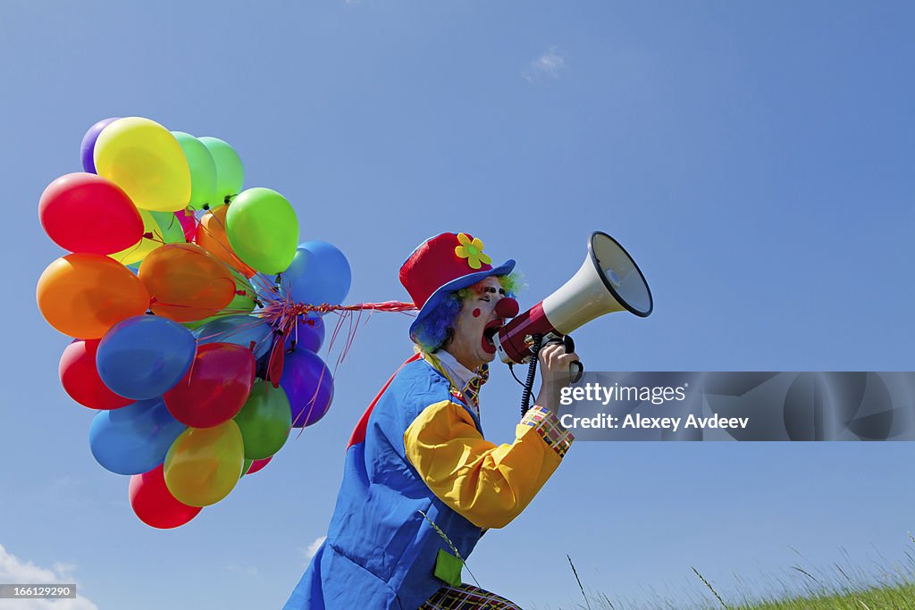 Clown holding balloons and crying to megaphone