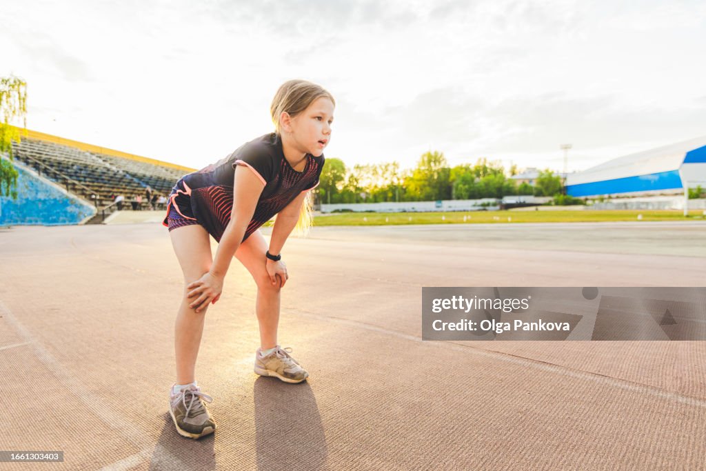Tired young girl athlete during a break of sports training at the stadium