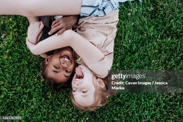 children laying in grass being silly - kind face stock pictures, royalty-free photos & images