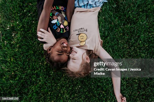 two girls laying in grass making silly face - preadolescent kind 個照片及圖片檔