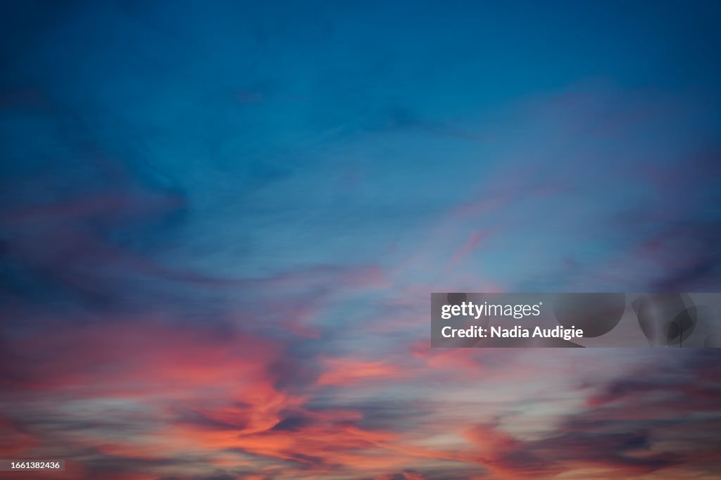 Dramatic clouds on a sunset sunrise sky with orange blue purple and pink etherial pastel background