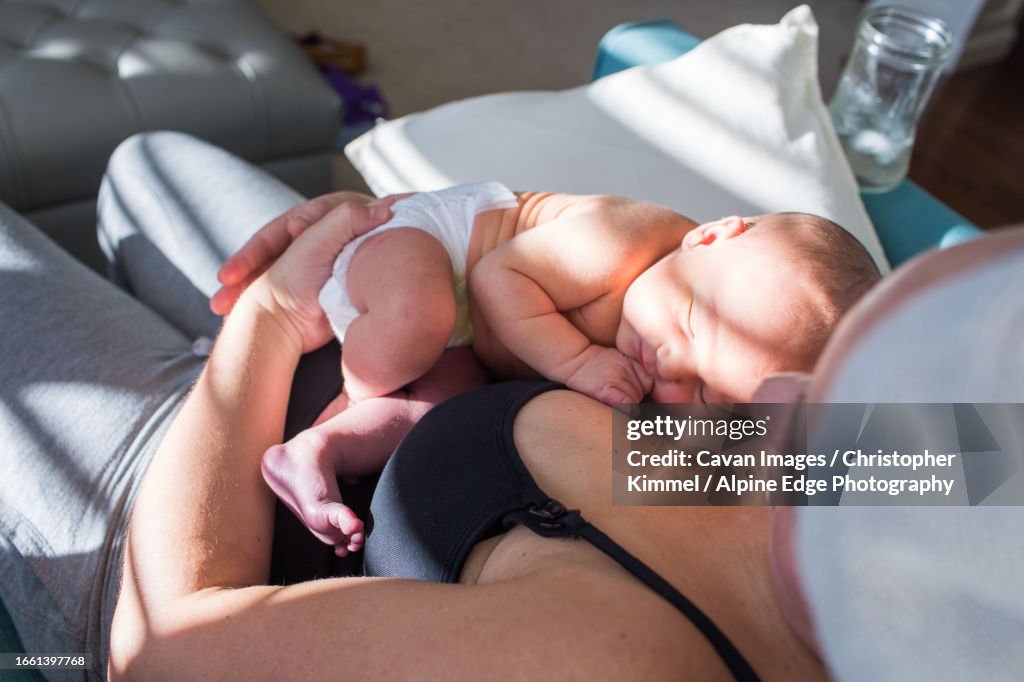 High angle view of new mother holding her sleeping newborn