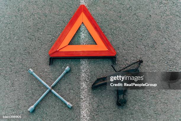 a closeup photograph captures a collection of essential tools alongside a prominent red warning triangle sign, illustrating preparedness for road emergencies - emergency sign stock pictures, royalty-free photos & images