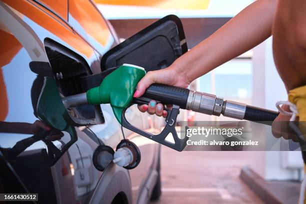 oil crisis raises price of diesel and gasoil - a woman filling the gas tank - petrol station stock pictures, royalty-free photos & images