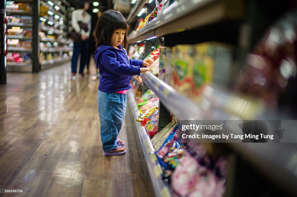 Toddler girl looking at candies on candy rack