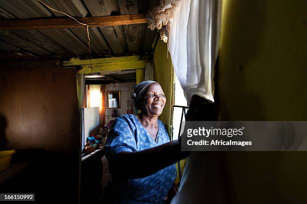 african woman looking out her window - gugulethu stockfoto's en -beelden
