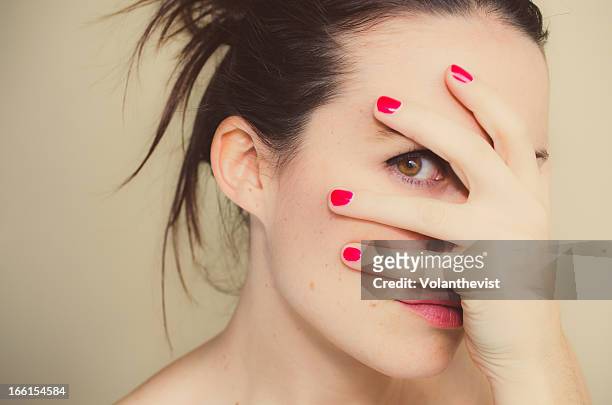 misterious girl with red nails and hand on face. - guilty stock-fotos und bilder