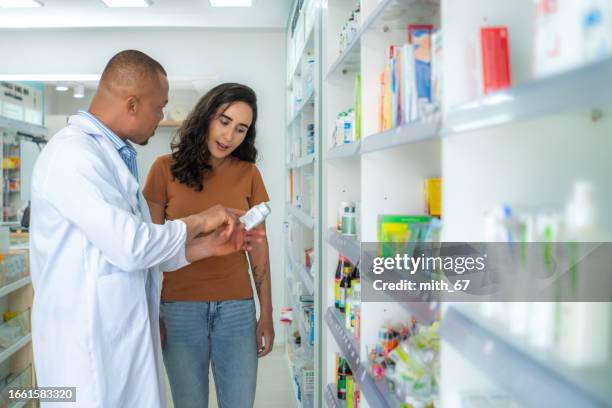 mid adult african american pharmacist male
explaining medication following the instruction from label in drug store. latin pharmacist man reading label and explaining instruction of drug while assisting a customer in a chemist. - latin american and hispanic shopping bags stockfoto's en -beelden