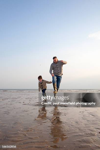 father and son jumping on sandy baech - jump dad stockfoto's en -beelden