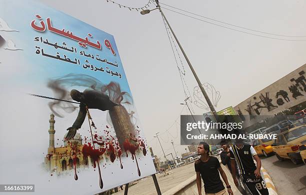 Iraqis look at a billboard depicting the fall of executed dictator Saddam Hussein's statue reading "April 9, the blood of martyrs transcended and the...