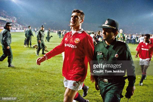 Manchester United player Eric Cantona is escorted from the pitch by a policeman after he was sent off at the end of the Champions League second round...