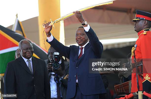 Kenya's fourth president Uhuru Kenyatta receives a sword as a symbol of authority from former president Mwai Kibaki during his inauguration at the...