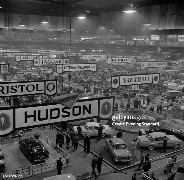 Visitors walking among exhibition stands showing new cars, signposted with various car brands at the London Motor Show, Earl's Court, October 1957.