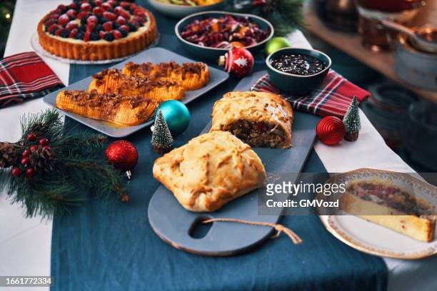 weihnachtsessen mit veganem pilz-rindfleisch wellington, butternusskürbis, grünen bohnen und beerenkuchen - pie stock-fotos und bilder