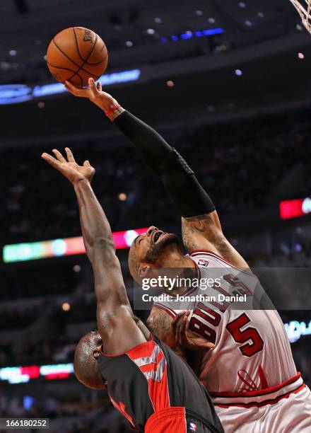 Carlos Boozer of the Chicago Bulls rebounds over Quincy Acy of the Toronto Raptors at the United Center on April 9, 2013 in Chicago, Illinois. NOTE...