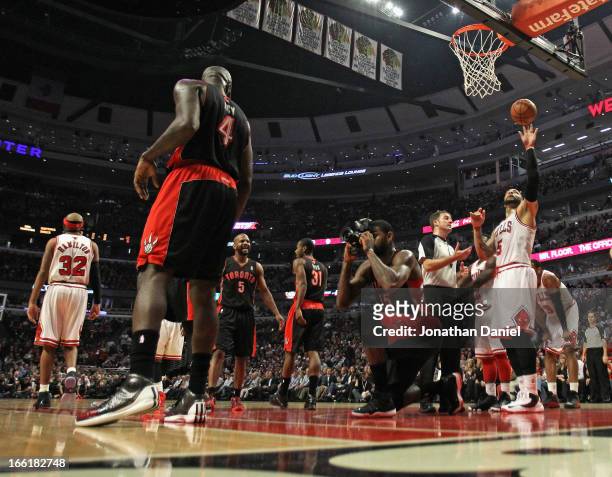 Amir Johnson of the Toronto Raptors pretends to take a picture with a remote camera that was kicked onto the floor during a game against the Chicago...