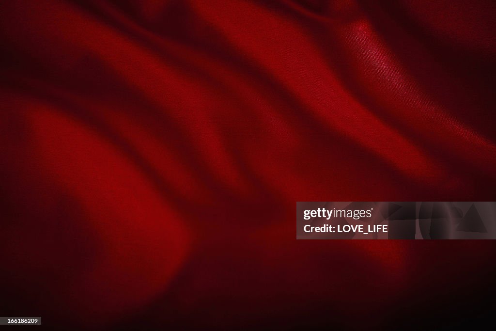 A red satin cloth background with wrinkles