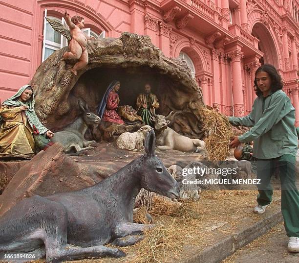 An employee of the President's house spreads hay in front of decorative manger installed in front of the the Pink House, by initiative of Ines...