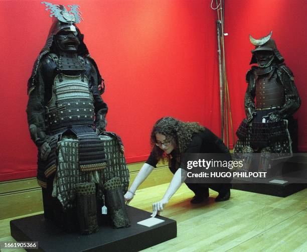 Christie's press officer Sophie Jepson pushes 02 June 2000 a Samurai warrior toward its allotted place for the press preview of "Arts of the Samurai"...