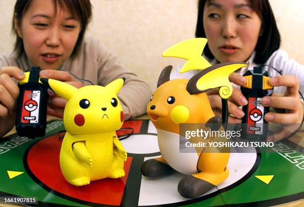 Japanese toy maker Tomy employees Kaori Kima and Mami Hashimoto demonstrate 20 December, 1999 the "Pokemon stadium, Pikachu vs Raichu" fighting game...