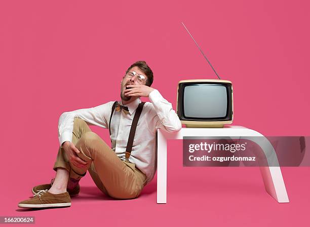 yawning young man sitting next to tv - pink tv stock pictures, royalty-free photos & images