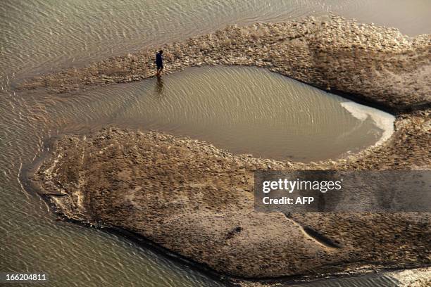 This picture taken on April 9, 2013 shows a man walking along the riverbed of the Hanjiang River during its dry season in Shiyan, central China's...