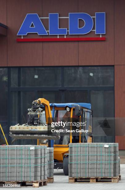 Workers prepare the future parking lot in front of a new Aldi Nord discount supermarket on the 100th anniversary of the chain on April 10, 2013 in...