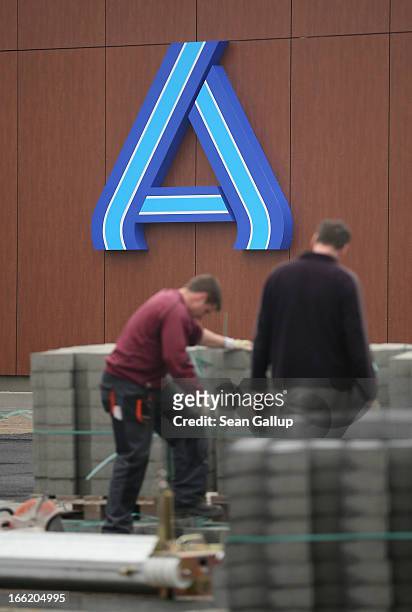 Workers prepare the future parking lot in front of a new Aldi Nord discount supermarket on the 100th anniversary of the chain on April 10, 2013 in...