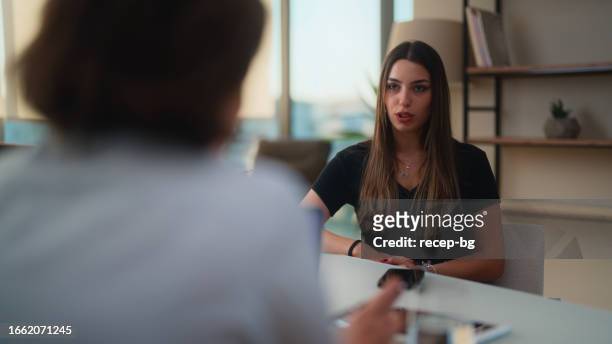 female university student visiting mental health professional - 50s woman writing at table stock pictures, royalty-free photos & images
