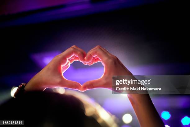 hand heart shape in the purple lighting of the concert hall. - lief stockfoto's en -beelden