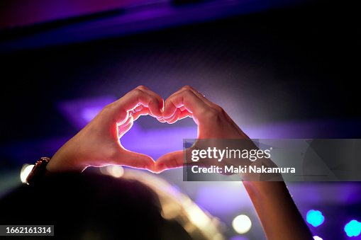 Hand heart shape in the purple lighting of the concert hall. Hand heart shape in the purple lighting of the concert hall.