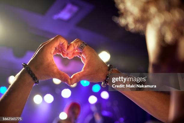 hand heart shape in the purple lighting of the concert hall. - truehearts stock pictures, royalty-free photos & images