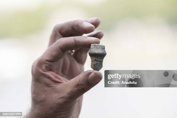 Man shows an object he unearthed from the Thames River bed after the water retreats in London, United Kingdom on September 11, 2023. For centuries,...