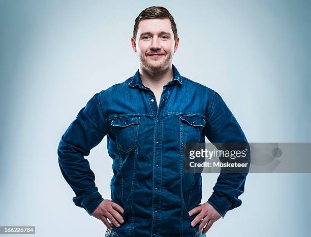 confident young man with hands on his hips - mann stolz stock-fotos und bilder