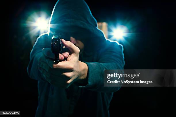 man in hood with revolver - armed robbery stock pictures, royalty-free photos & images