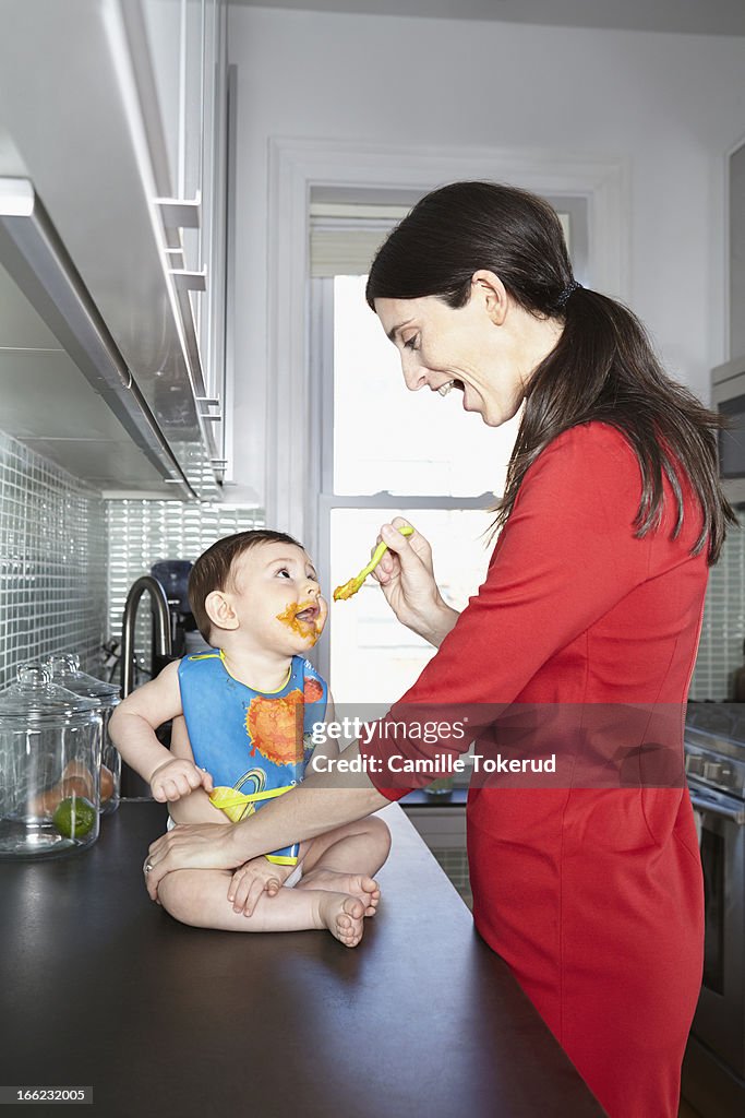 Mother feeding baby in kitchen