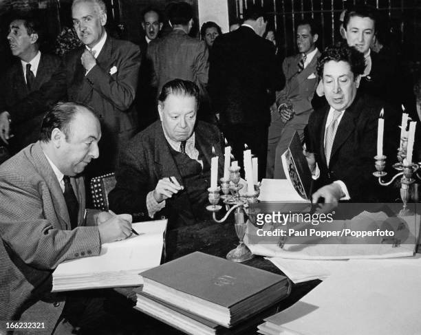 Chilean poet, diplomat and politician Pablo Neruda and Mexican painters Diego Rivera and David Alfaro Siqueiros sign copies of Neruda's latest poetry...