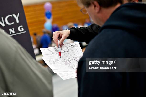 Kelly Davis, regional manager for The Agency Staffing, points out the skills section on an application as he talks with a job seeker during a job...