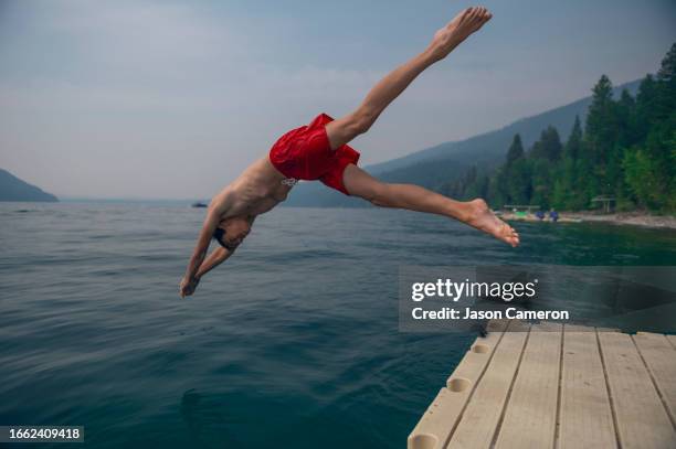 a teenage boy y-leg diving into a scenic mountain lake - lake whitefish stock-fotos und bilder