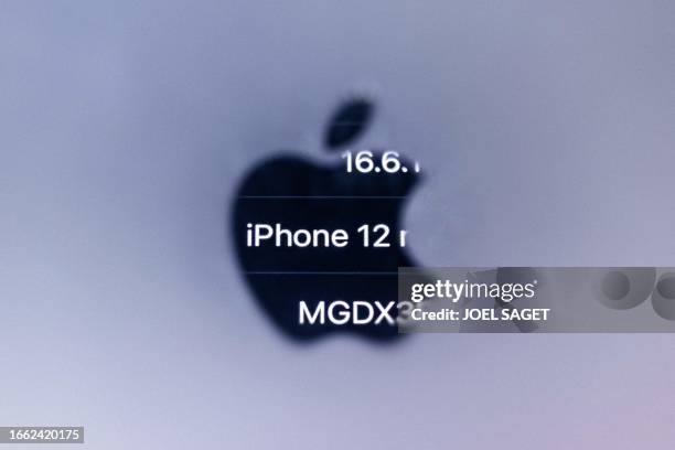 This illustration photograph taken on September 13, 2023 in Paris with a macro lens shows reversed information of an iPhone 12 reflected in the Apple...