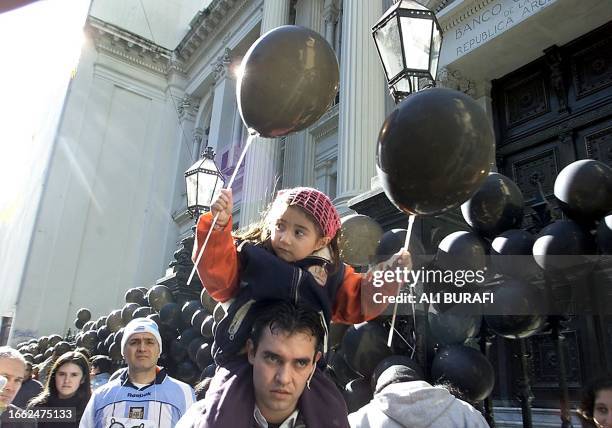 Scotiabank employee carries his daughter on his shoulders in front of the Banco Central de la Republica Argentina, in Buenos Aires, 18 July 2002....