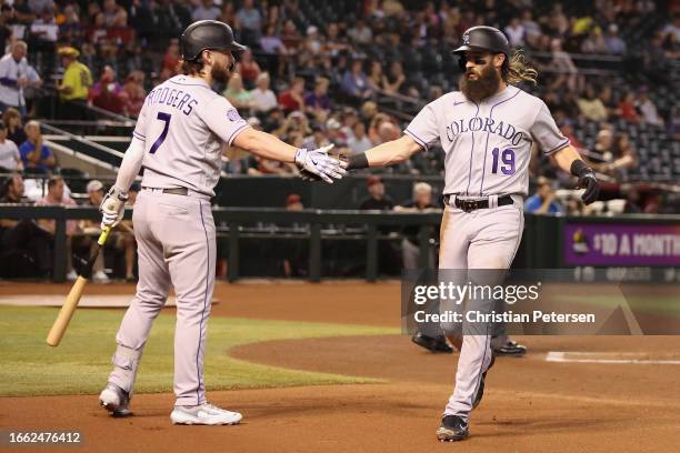 Charlie Blackmon of the Colorado Rockies high fives Brendan Rodgers after scoring a run against the Arizona Diamondbacks during the first inning of...