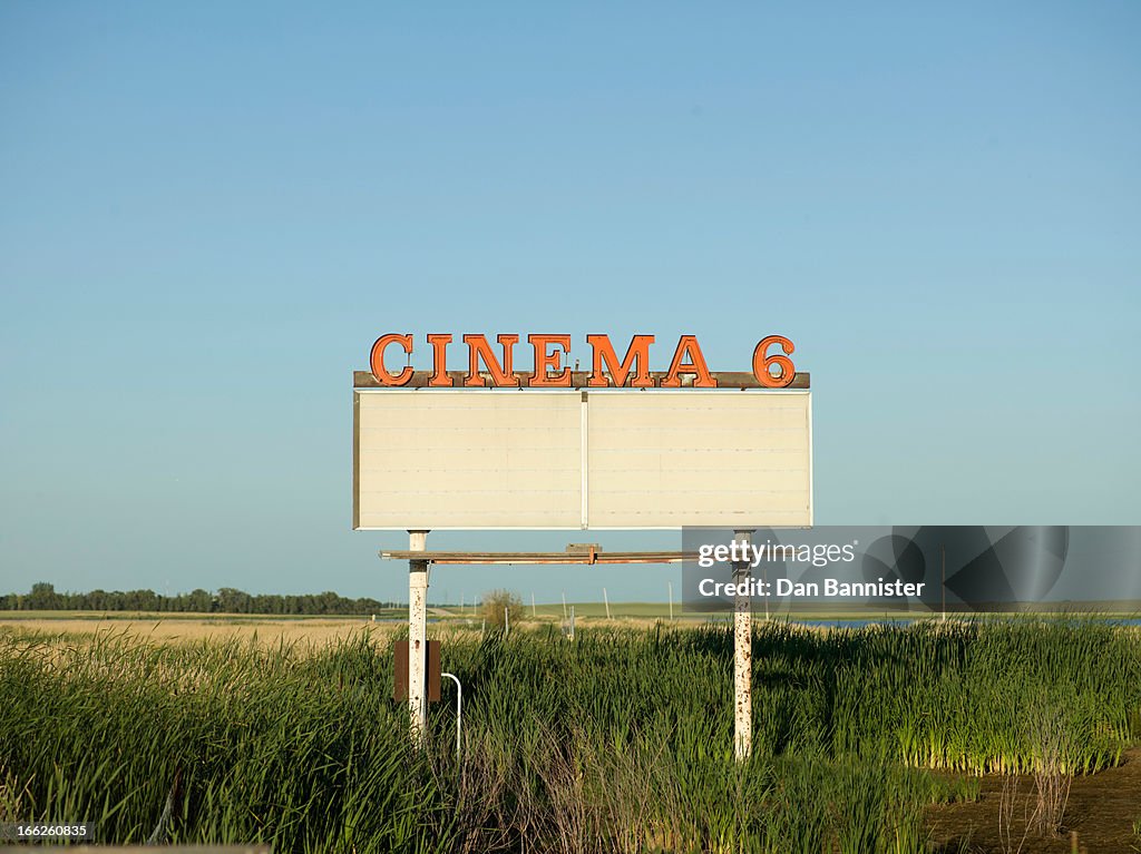 Abandoned drive-in movie sign in field