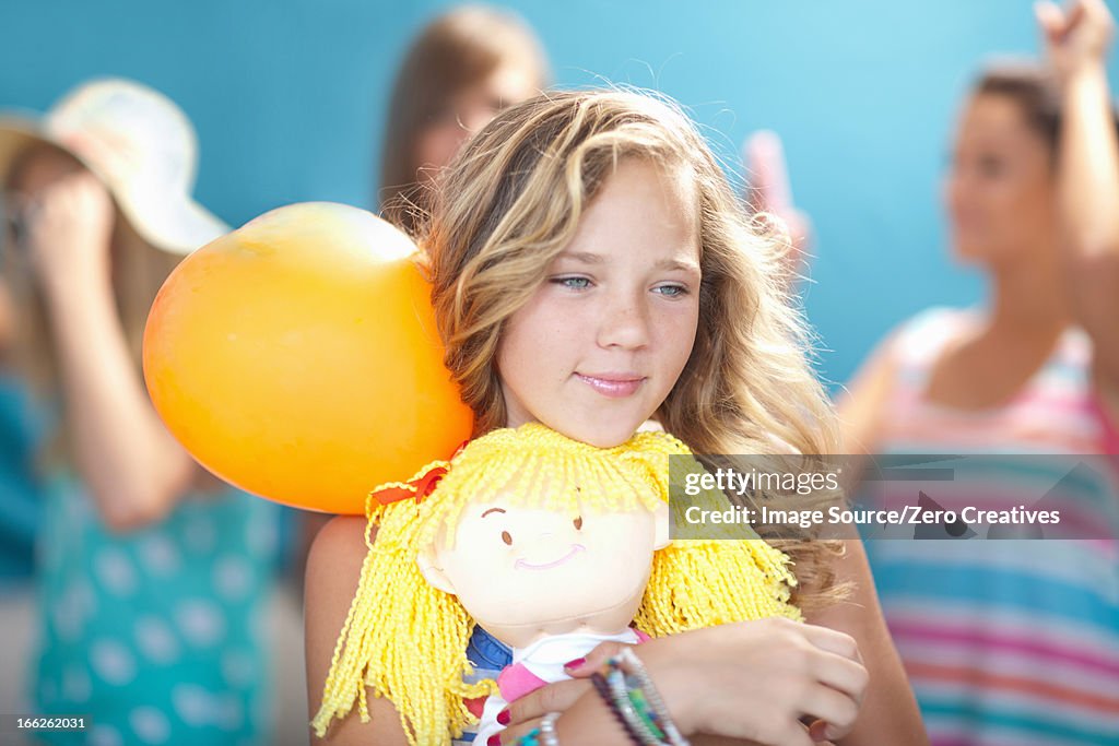 Smiling girl holding balloon and doll