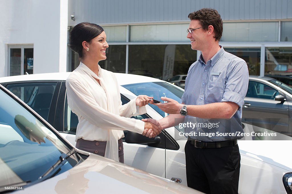 Woman buying new car from salesman