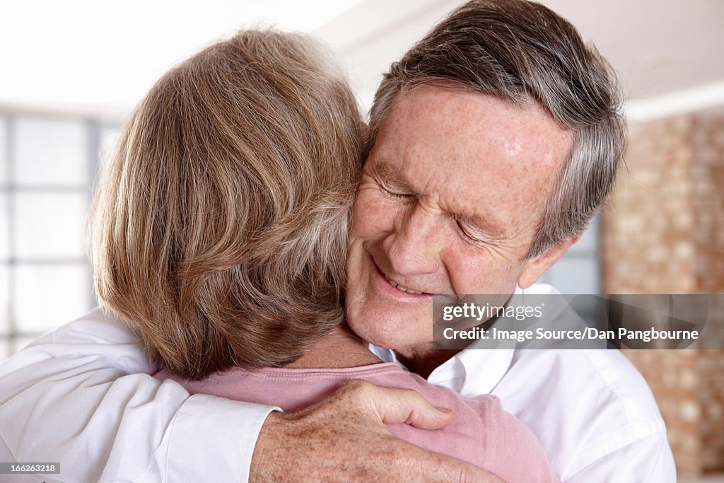 Older couple hugging in living room