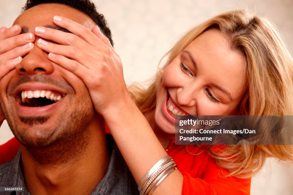 Woman covering boyfriend's eyes