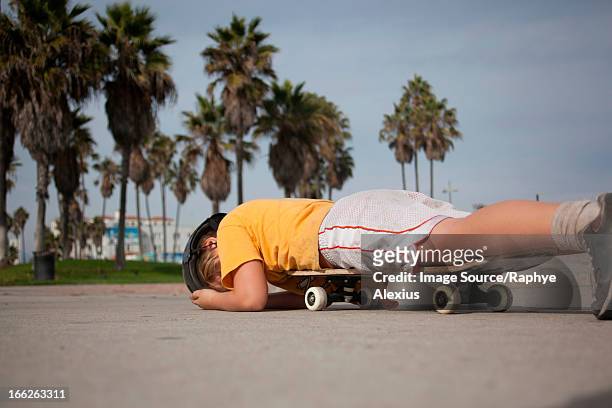 boy laying on skateboard in park - skate fail stock-fotos und bilder