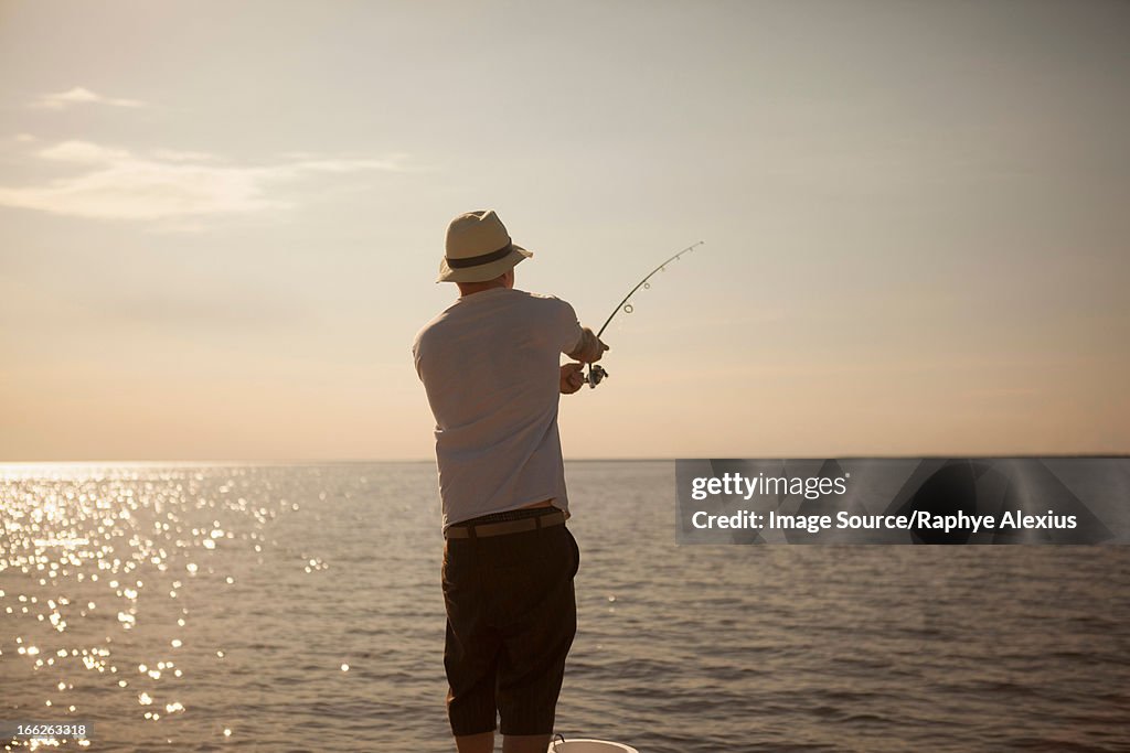 Man fishing in still ocean